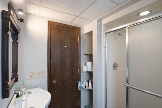 bathroom with walk in shower, sink, and a drop ceiling