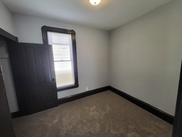 spare room featuring dark colored carpet