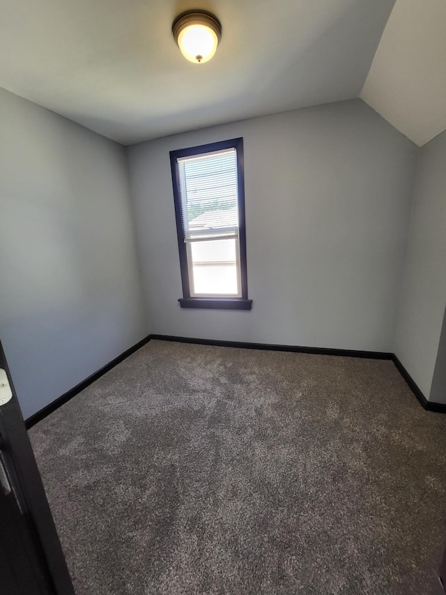 empty room with lofted ceiling and dark carpet