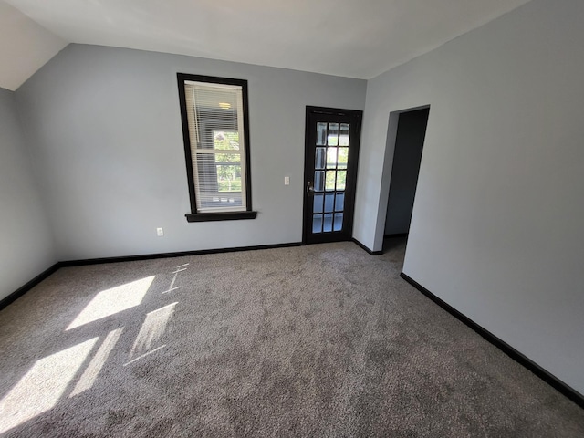 carpeted empty room with lofted ceiling