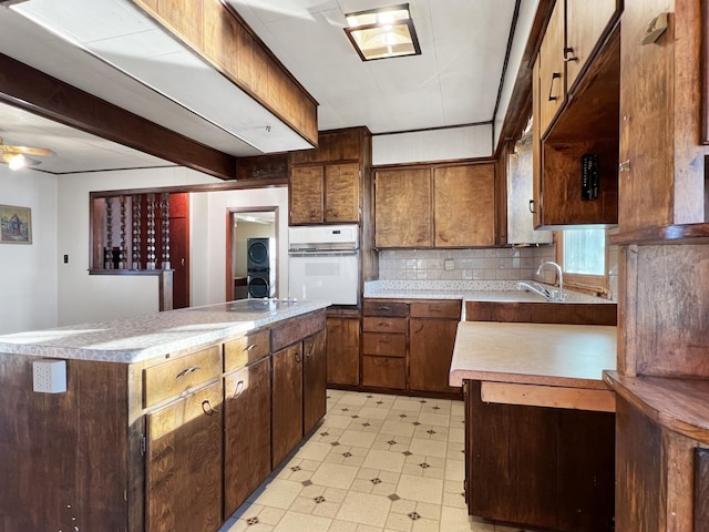 kitchen with tasteful backsplash, white oven, a kitchen island, stacked washer and dryer, and ceiling fan