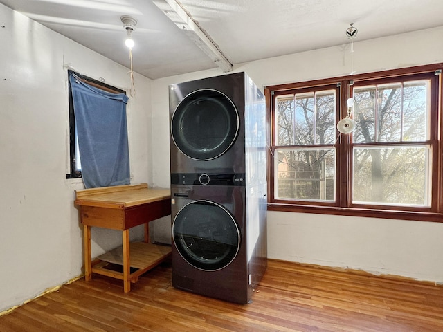 clothes washing area with stacked washer / drying machine and hardwood / wood-style flooring