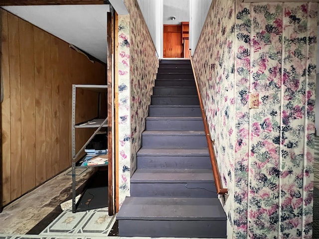 stairs featuring concrete flooring and wooden walls