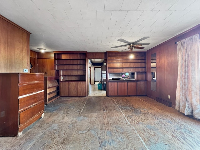 interior space with built in features, wood walls, and ceiling fan