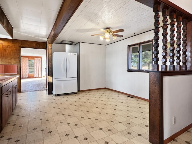 kitchen with plenty of natural light, wooden walls, ceiling fan, and white fridge