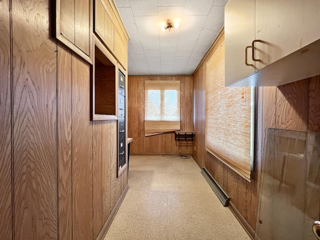 hallway with a baseboard heating unit and wooden walls