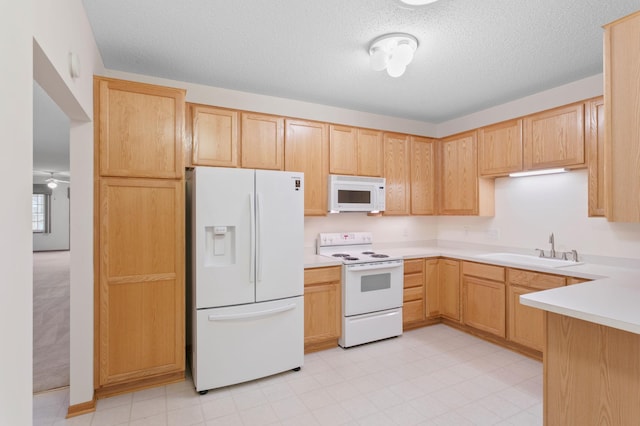 kitchen featuring a textured ceiling, light brown cabinets, white appliances, and sink