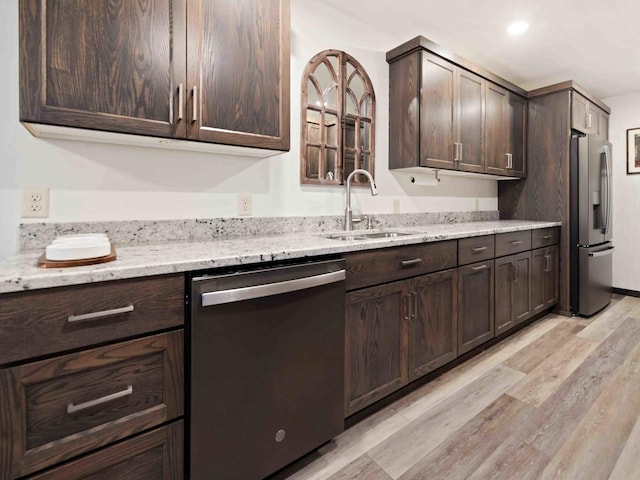 kitchen with dark brown cabinetry, sink, light stone counters, appliances with stainless steel finishes, and light wood-type flooring