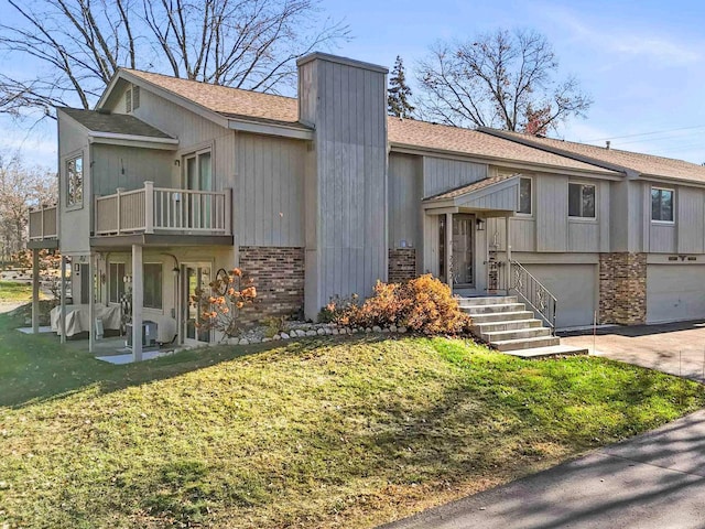 view of front facade featuring a garage, a balcony, and a front yard