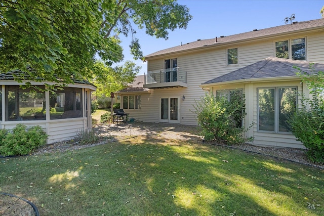 back of property with a balcony, a lawn, and a sunroom