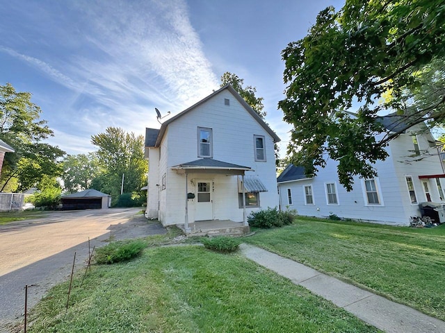 view of front of property with a front yard, an outdoor structure, and a garage