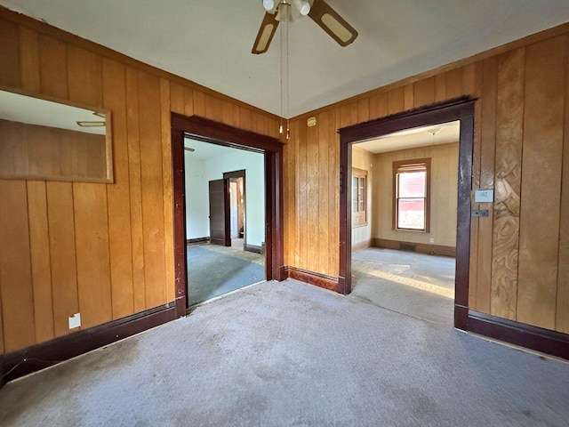 spare room with wood walls, carpet, and ceiling fan