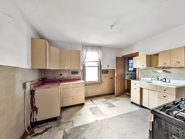 717 Jefferson Ave, Albert Lea, MN 56007 - kitchen featuring wainscoting, gas stove, cream cabinets, tile walls, and light countertops