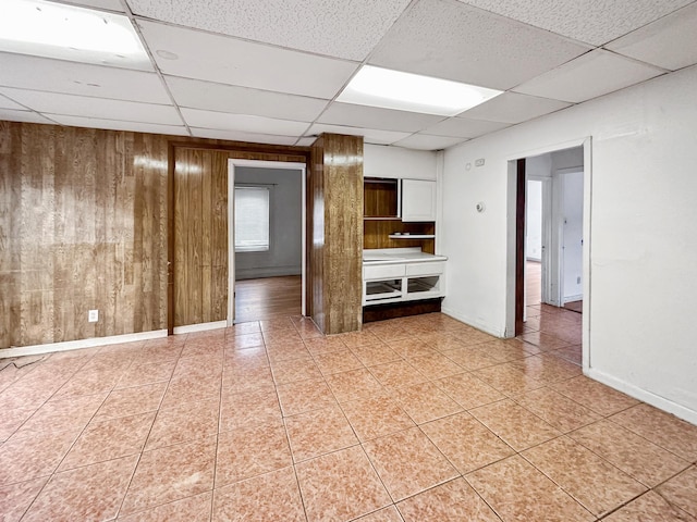 spare room featuring a paneled ceiling and wood walls