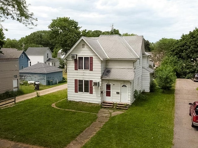 view of front facade featuring a wall unit AC and a front yard