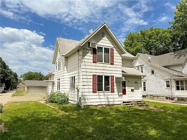 view of front of house featuring a garage, a front yard, and an outbuilding