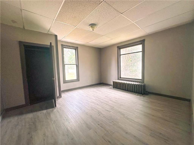 404 Main St, Austin, MN 55912 - unfurnished bedroom with radiator heating unit, a drop ceiling, wood finished floors, and baseboards