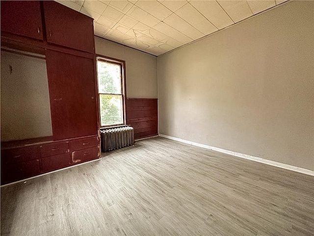 404 Main St, Austin, MN 55912 - empty room with radiator, wood finished floors, baseboards, and wainscoting