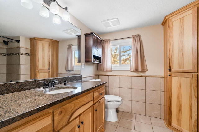 bathroom featuring tile walls, vanity, tile patterned floors, and toilet