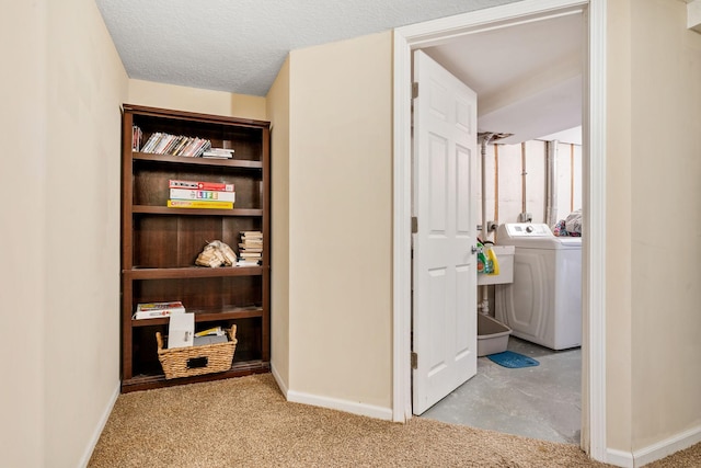 hall with washer / clothes dryer, light colored carpet, and a textured ceiling