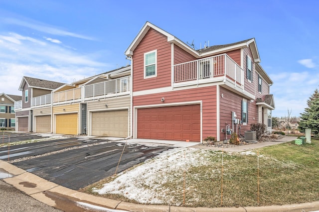 view of front of property featuring central AC, a balcony, and a garage