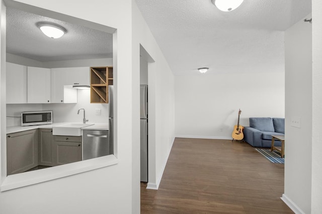 kitchen featuring white cabinetry, sink, appliances with stainless steel finishes, dark hardwood / wood-style floors, and a textured ceiling