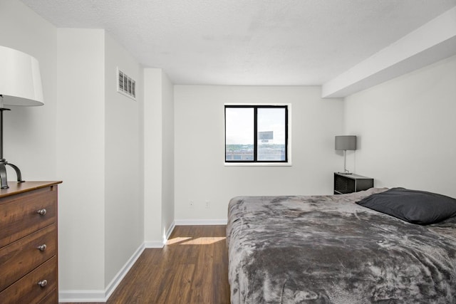 bedroom featuring a textured ceiling and dark hardwood / wood-style floors