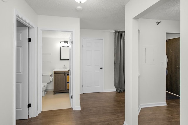 hallway featuring dark hardwood / wood-style flooring, a textured ceiling, and sink