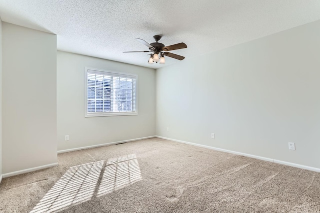 spare room with carpet floors, a textured ceiling, baseboards, and a ceiling fan