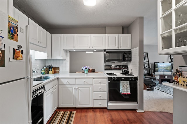 kitchen featuring tasteful backsplash, dark wood-type flooring, sink, black appliances, and white cabinetry