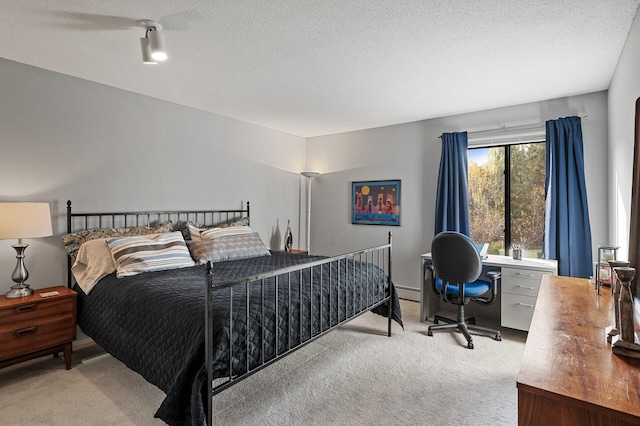 carpeted bedroom with a textured ceiling and a baseboard heating unit