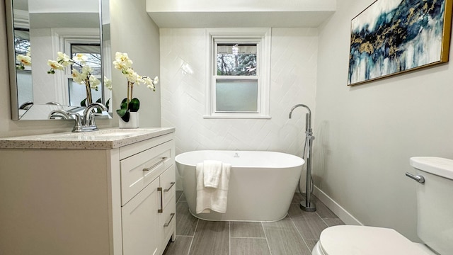 bathroom with a bath, vanity, toilet, and tile walls