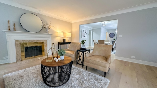 sitting room with light wood-type flooring, a premium fireplace, and crown molding