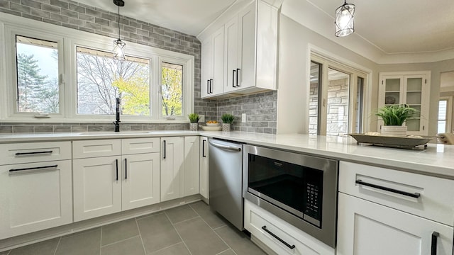 kitchen with sink, stainless steel appliances, tasteful backsplash, decorative light fixtures, and white cabinets