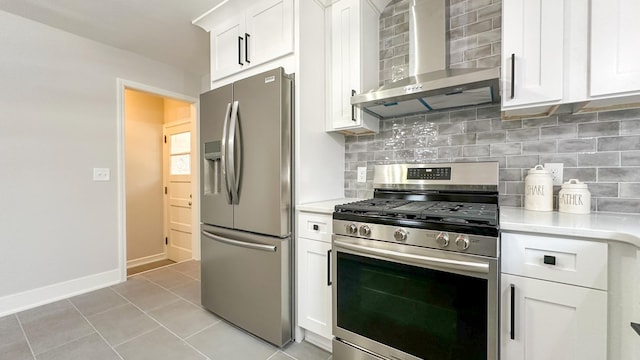 kitchen featuring white cabinets, wall chimney exhaust hood, tasteful backsplash, light tile patterned flooring, and stainless steel appliances