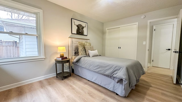 bedroom with light hardwood / wood-style floors, a textured ceiling, and a closet