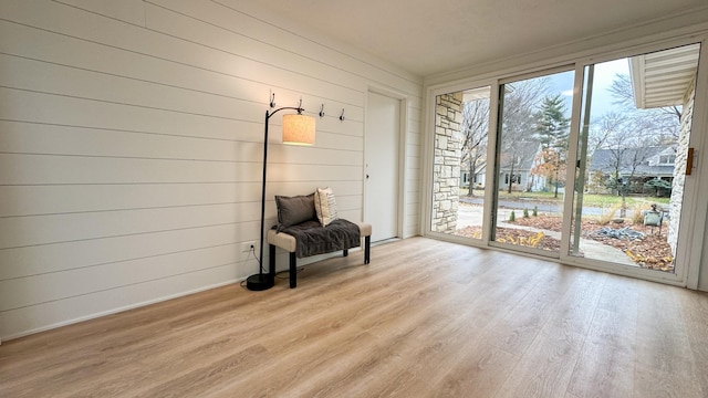 unfurnished room featuring light hardwood / wood-style flooring and wood walls