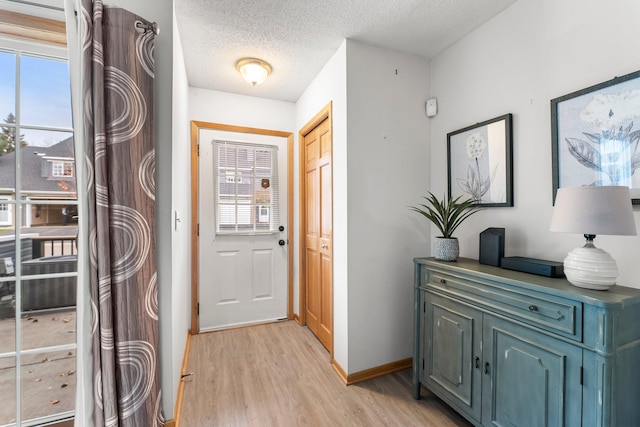 entryway with a wealth of natural light, a textured ceiling, and light hardwood / wood-style flooring