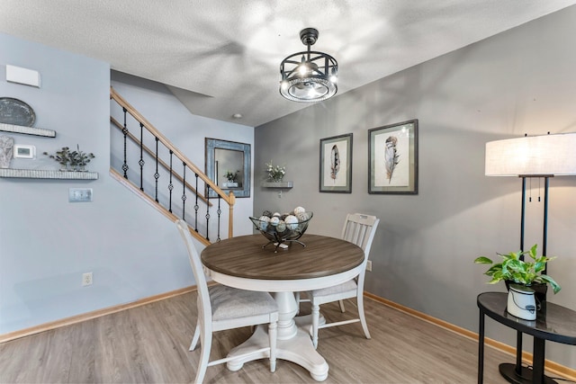 dining space with light hardwood / wood-style floors and a textured ceiling