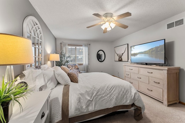 bedroom featuring ceiling fan, a textured ceiling, and light colored carpet