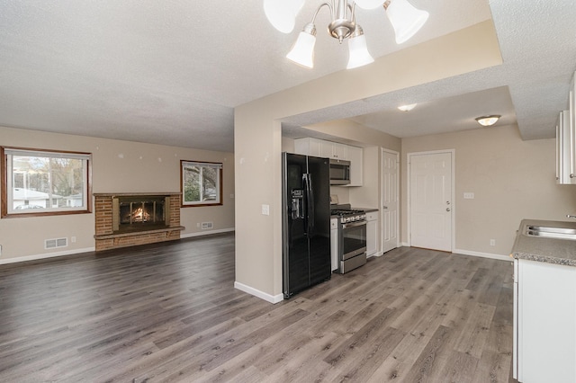 kitchen featuring hardwood / wood-style floors, sink, a textured ceiling, white cabinetry, and stainless steel appliances