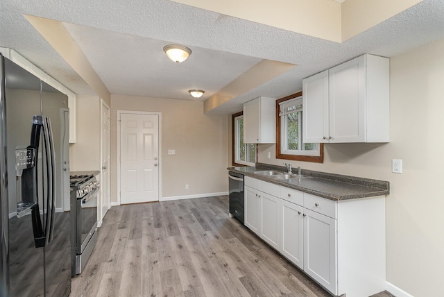 kitchen featuring white cabinets, light wood-type flooring, a textured ceiling, and appliances with stainless steel finishes