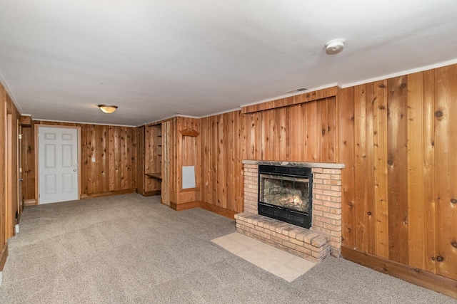 unfurnished living room with crown molding, wooden walls, a fireplace, and light carpet