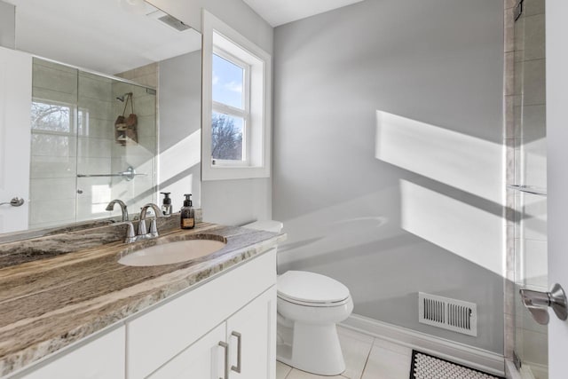 bathroom featuring toilet, vanity, a shower with door, and tile patterned floors