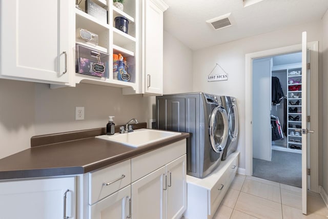 laundry area featuring independent washer and dryer, light tile patterned flooring, sink, a textured ceiling, and cabinets