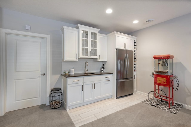 kitchen with sink, white cabinets, stainless steel fridge, and light colored carpet