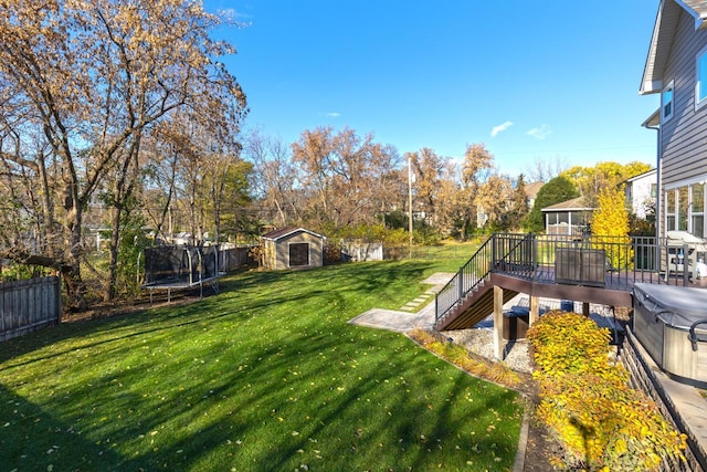 view of yard with a wooden deck, a storage unit, and a trampoline