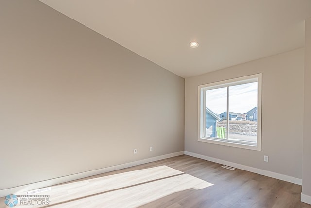 empty room featuring light hardwood / wood-style flooring and vaulted ceiling