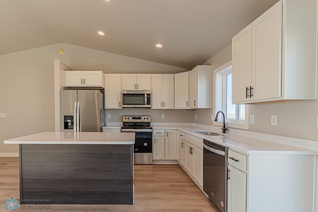 kitchen featuring vaulted ceiling, white cabinetry, a kitchen island, and appliances with stainless steel finishes