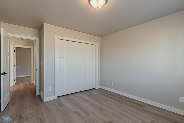 unfurnished bedroom with light hardwood / wood-style flooring and a closet